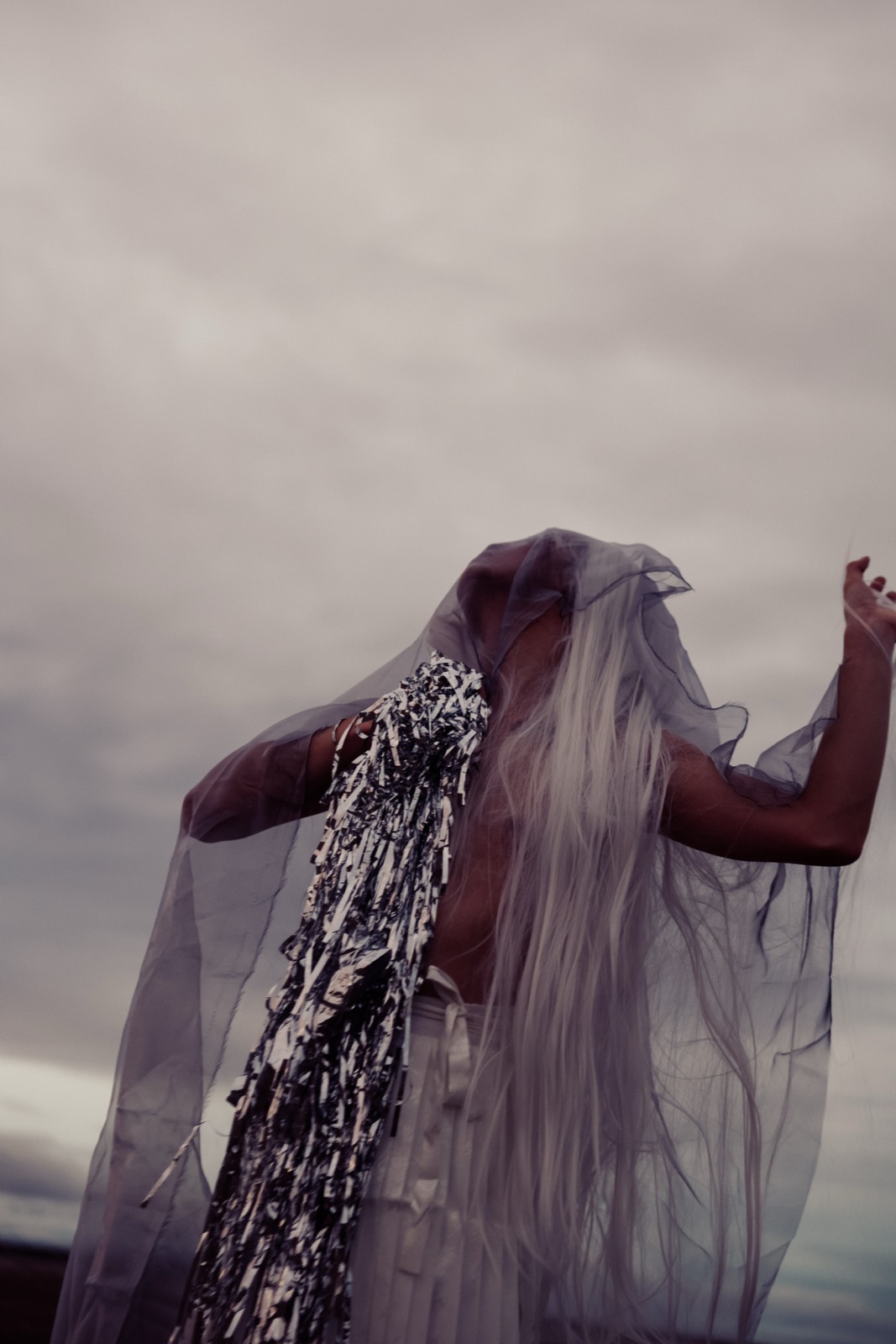 A veiled figure beneath a gray sky