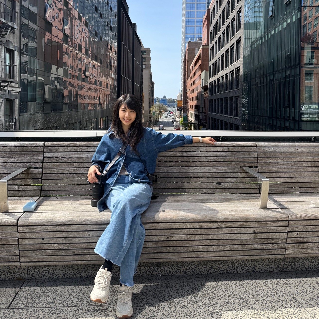 Nikita sitting on a city bench with her camera